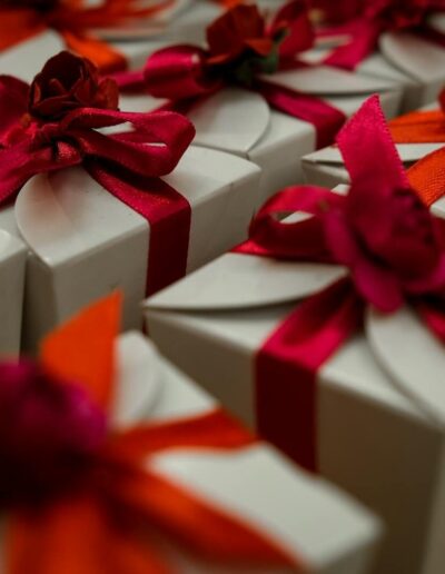 Close-up of white gift boxes adorned with vibrant red and orange ribbons, ideal for celebrations.